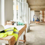 Roupa e capacete em cima de mesa de madeira em meio a uma obra