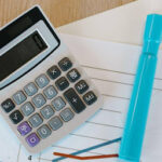 Calculadora e caneta em cima de folha de caderno