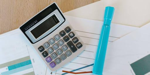 Calculadora e caneta em cima de folha de caderno