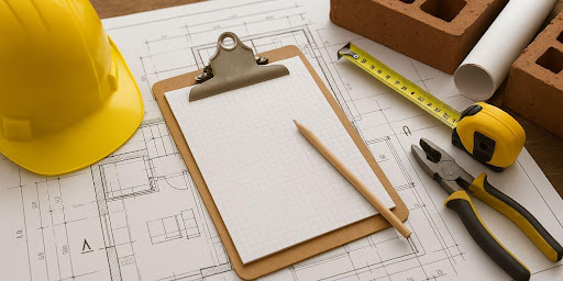 Ambiente antigo em reforma com capacete e ferramentas no chão.