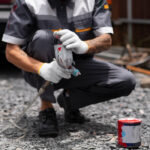 Homem aplicando primer asfáltico no chão